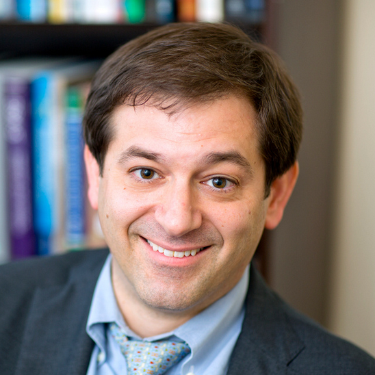 Psychiatrist in clinical office setting with medical books in the background