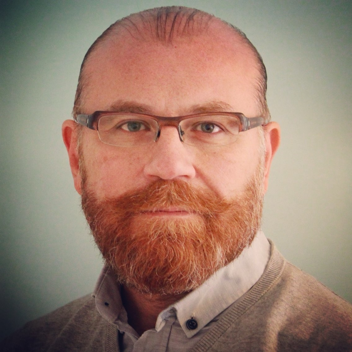 Psychiatrist in clinical office setting wearing glasses and a sweater